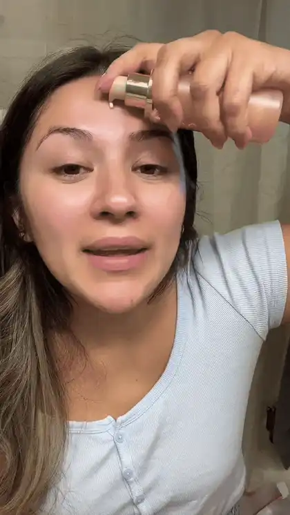 A customer applying VYRA™ foundation from the bottle to her forehead